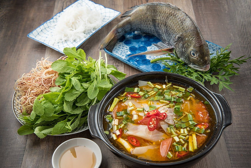 Fresh fish soup with vegetables and noodles on wooden table