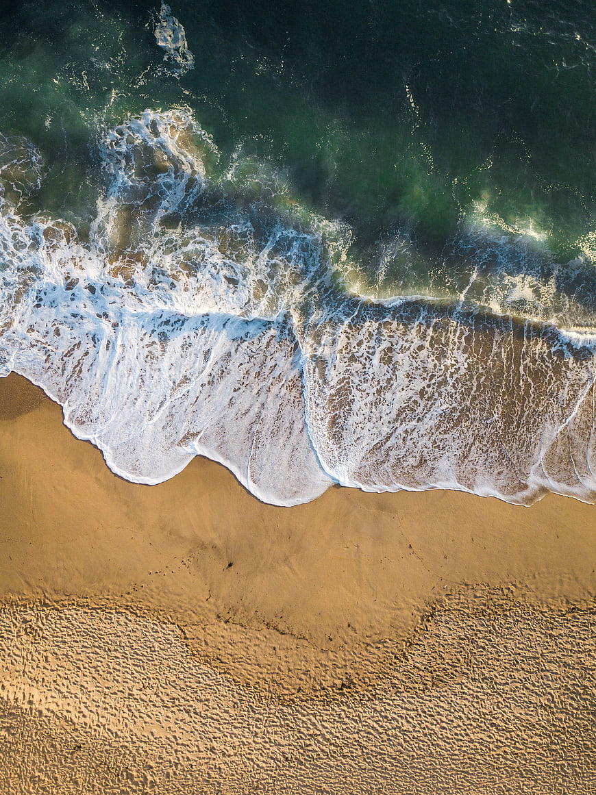 Aerial View of Ocean Waves Crashing on Sandy Beach