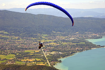 Paraglider soaring over scenic lake and mountain landscape