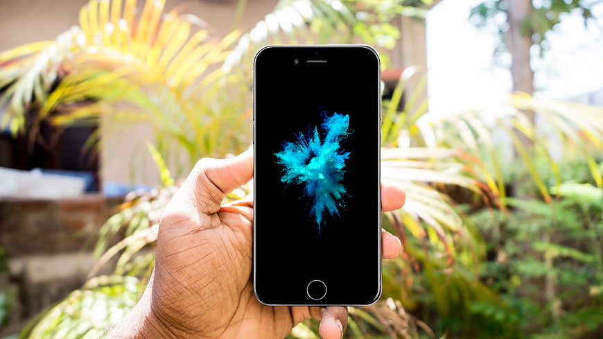 Hand holding smartphone with blue abstract screen outdoors