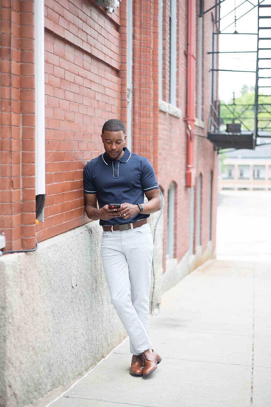 Stylish Black Man Using Smartphone Against Brick Wall