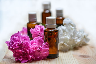 Essential Oil Bottles with Pink and White Flowers on Wood