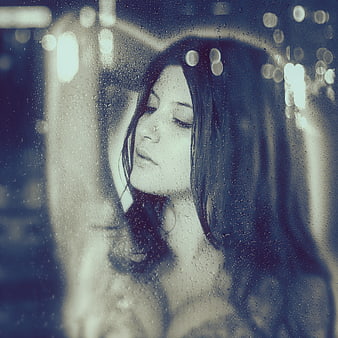Melancholic Woman Looking Out Rainy Window at Night