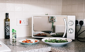 Healthy salad and ingredients on kitchen counter with microwave