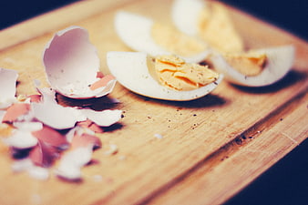 Boiled eggs and shells on wooden cutting board