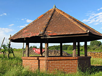 Rustic brick well house with tiled roof in vineyard