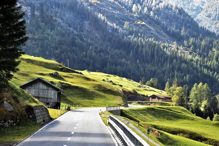 Alpine Mountain Road With Green Pastures And Snowy Peaks