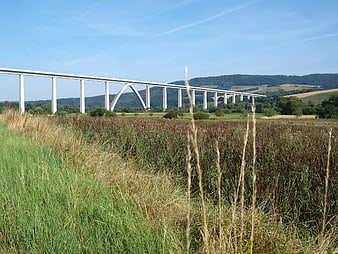 Modern concrete viaduct spanning green valley landscape