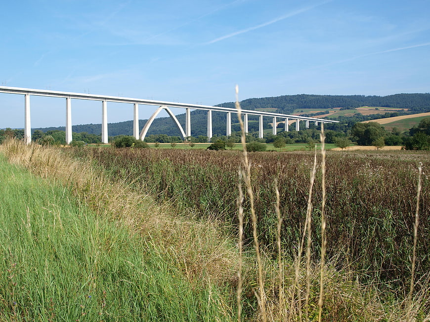 Modern concrete viaduct spanning green valley landscape
