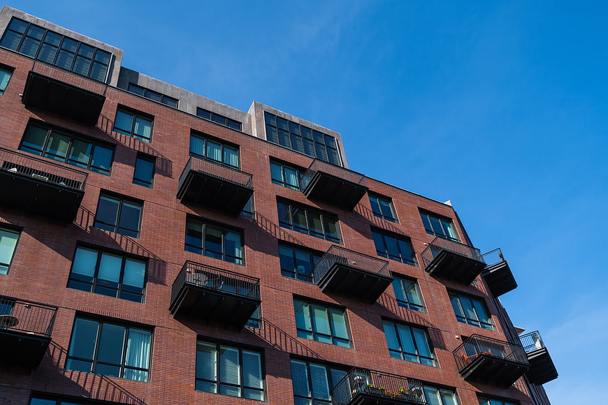 Modern Brick Apartment Building with Balconies Against Blue Sky