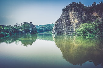 Serene tropical river with limestone cliffs and lush green reflections