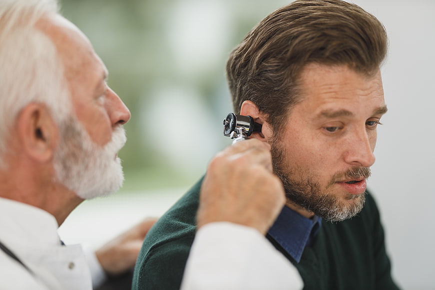 Doctor examining patient's ear with otoscope