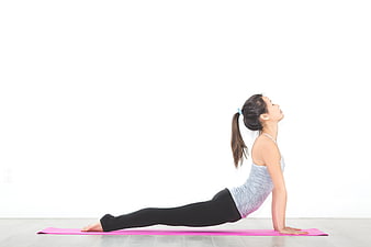 Woman performing cobra yoga pose on pink mat