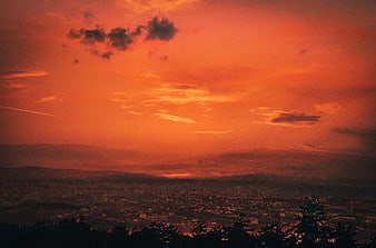 Dramatic Orange Sunset Over City and Mountains