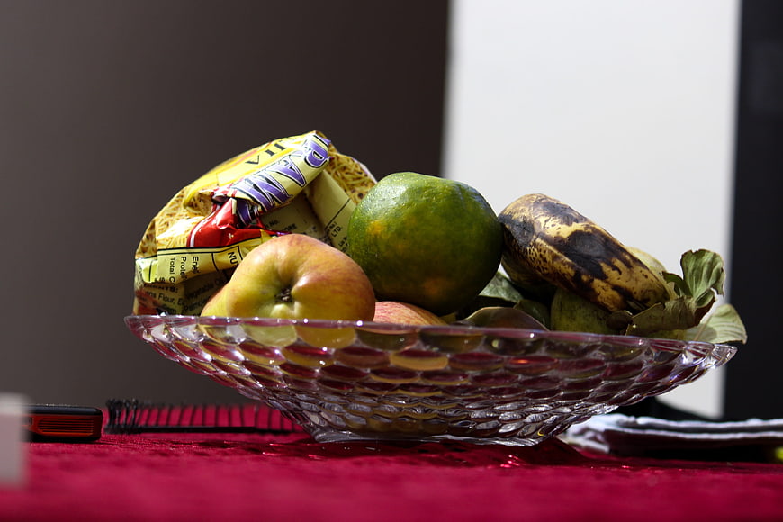 Glass bowl of fruit and bread on red tablecloth