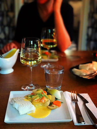 Gourmet fish dinner with wine and vegetables on wooden table