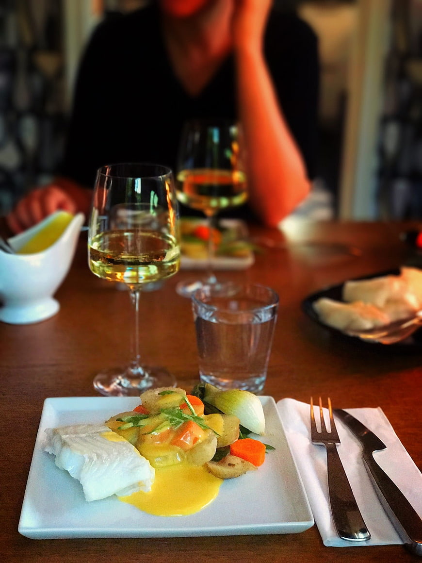 Gourmet fish dinner with wine and vegetables on wooden table