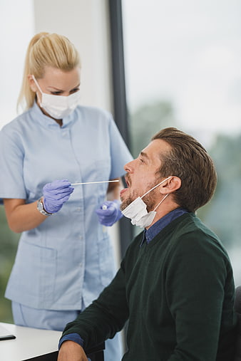 Nurse performing throat swab test on male patient
