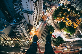 First-person view of legs dangling over city at night