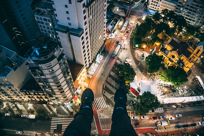 First-person view of legs dangling over city at night