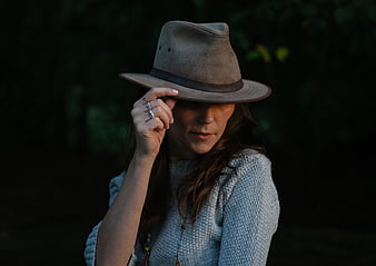 Woman in Fedora Hat Holding Brim in Dark Forest