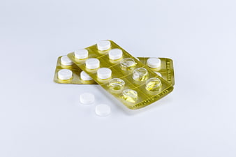 White Pills In Gold Blister Pack On White Background