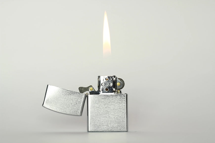 Silver Flip Top Lighter with Flame on White Background