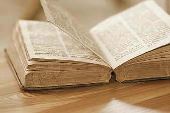 Open antique leather-bound book with historical text on wooden table