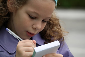 Close-up of young girl writing in notebook outdoors