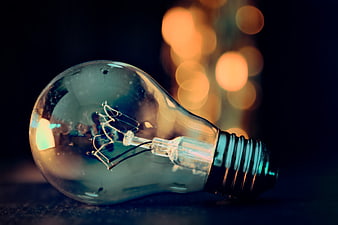 Unlit incandescent light bulb with warm bokeh background
