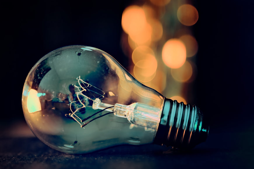 Unlit incandescent light bulb with warm bokeh background