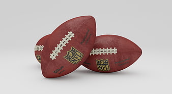 Three NFL Wilson Footballs on Gray Background