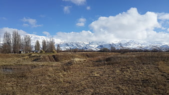 Snowy Mountain Range Over Brown Winter Field