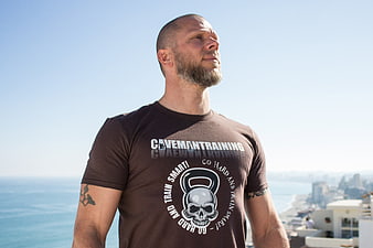 Muscular man in Caveman Training t-shirt standing outdoors