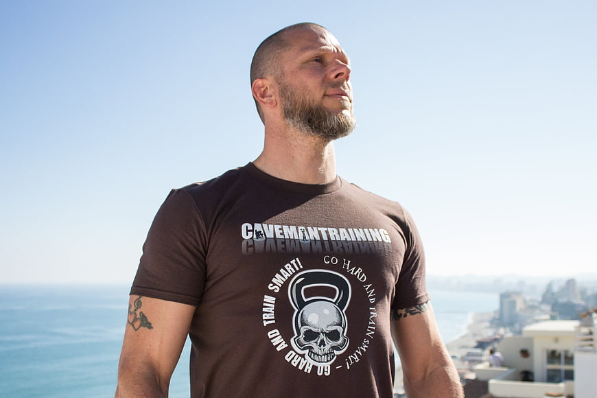Muscular man in Caveman Training t-shirt standing outdoors