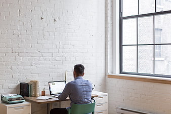 Man working on laptop in bright white brick office