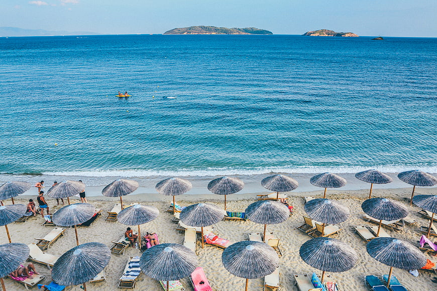 Aerial View of Beach with Straw Umbrellas and Blue Sea