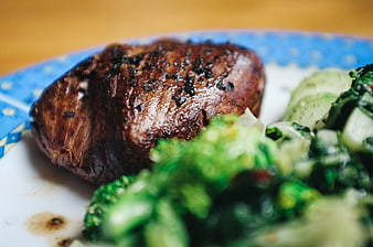 Close-up of grilled beef steak with broccoli on a blue plate