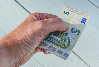 Hand holding five euro banknote on white background