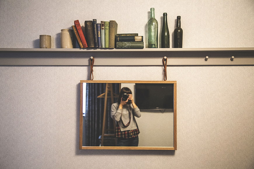 Woman taking mirror selfie with camera in vintage room