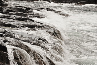 Powerful white water rapids crashing over dark rocks