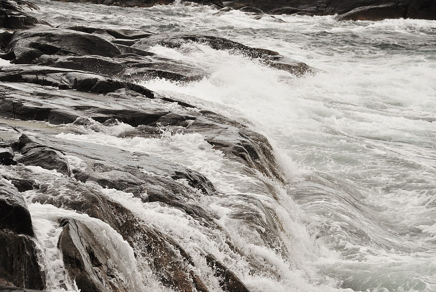 Powerful white water rapids crashing over dark rocks