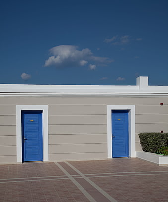 Modern beige building with blue doors and blue sky