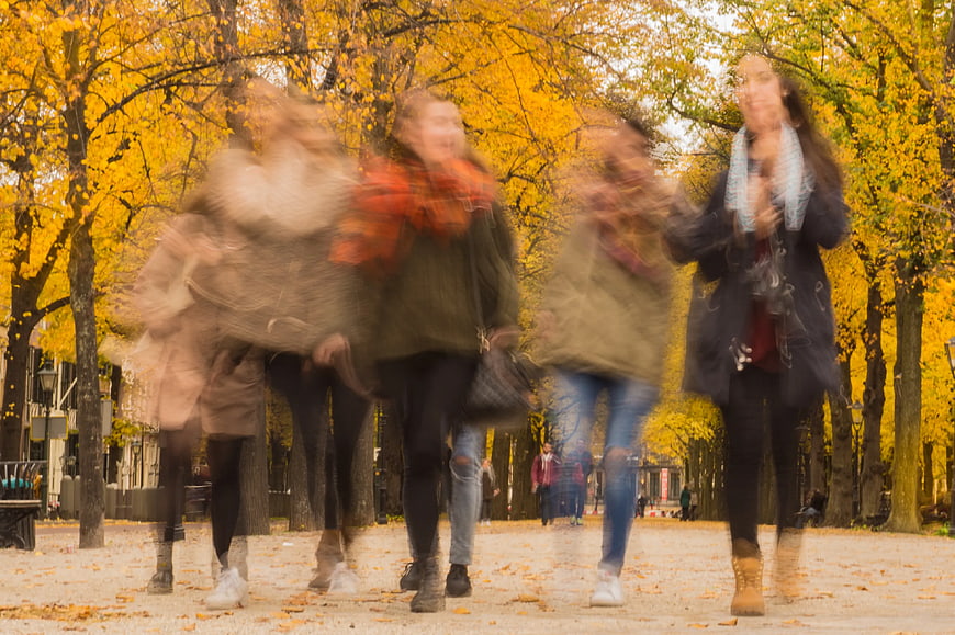Motion blur group of friends walking in autumn park