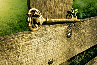 Vintage golden key resting on weathered wooden fence
