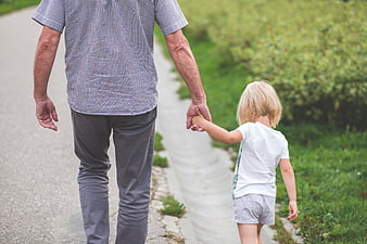 Senior man and young child holding hands walking outdoors