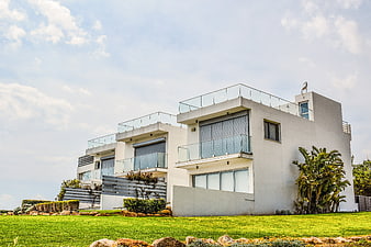 Modern white villa with glass balconies on green lawn