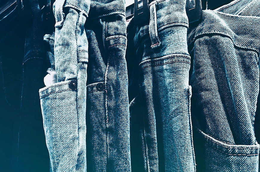 Close-up of hanging blue denim jeans on a rack