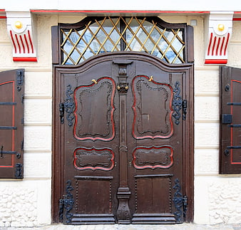Ornate brown wooden double doors with red accents