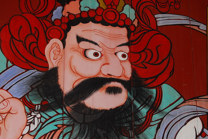 Close-up of fierce traditional Asian temple guardian deity mural